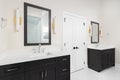 A bathroom with dark grey cabinets, gold sconces, and marble floor.