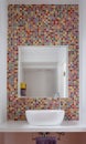 Bathroom wash basin with colorful glass mosaic tiles and mirror inset into the tiles Royalty Free Stock Photo