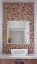 Bathroom wash basin with colorful glass mosaic tiles and mirror inset into the tiles Royalty Free Stock Photo