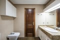 Bathroom in white and cream tones with wooden sink cabinet with marble top, white porcelain sink, integrated mirror and sapele Royalty Free Stock Photo