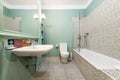 Bathroom with white porcelain hanging sink, large green-framed mirror,