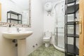 Bathroom with white porcelain one-piece pedestal sink and valance-framed wall mirror, corner shower stall and black metal shelving