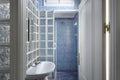 Bathroom with white porcelain sink with glass paves brick walls, blue tiled