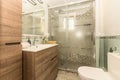 Bathroom with white porcelain sink with large wood-drawer cabinets, frameless mirror and valance on wall, and walk-in shower with Royalty Free Stock Photo