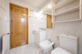 Bathroom with white porcelain sink with marble top and white wooden cabinet with drawers, mirror with matching sconces and wooden Royalty Free Stock Photo