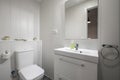 Bathroom with white porcelain sink on white wood cabinet, square frameless