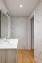 Bathroom with white tiles, mirror, ceramic sink under a wardrobe in a modern house or office. Royalty Free Stock Photo