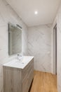 Bathroom with white tiles, mirror, ceramic sink under a wardrobe in a modern house or office. Royalty Free Stock Photo