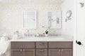 A bathroom with a wood cabinet and floral wallpaper.