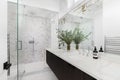 A bathroom with a wood cabinet, marble countertop, and herringbone tiled shower. Royalty Free Stock Photo