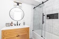 A bathroom with a wood cabinet and marble subway tile shower. Royalty Free Stock Photo