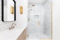 A bathroom with gold faucets and a shower lined with marble tiles. Royalty Free Stock Photo