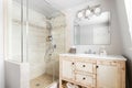 A bathroom with a wood cabinet and tiled walk-in shower. Royalty Free Stock Photo