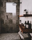 Bathroom wooden shelves with bath utensils and cosmetics in modern gray bathroom with shower and pebbles on floor, contemporary