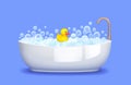 Bathtub with foam, soap bubbles and yellow rubber duck isolated on blue background. Bathing and relaxing Royalty Free Stock Photo