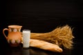 Batons, a pitcher, a glass of milk and a sheaf on a black background