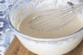 Batter mix in a glass bowl with a metal whisk. On a blue tiled worktop Royalty Free Stock Photo