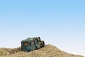 Battered Blue Toy Car in Sand Pit Against Blue Sky