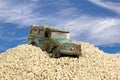 Battered Blue Toy Car in Sand Pit Against Blue Sky