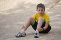 Battered boy sits on the ground with a scratched face and a sad look Royalty Free Stock Photo