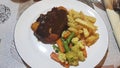 Battered chicken, fried potatoes and boiled cauliflower and carrots on a white plate.