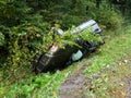 A Battered Gray Car Sedan Lies In A Roadside Ditch Among The Lush Green Foliage Of The Bush In The Summer. Road Traffic Incident.