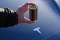 4680 battery for electric vehicles in male hand, blue electric car tesla company Elon Musk, alternative energy development concept