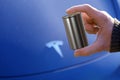 4680 battery for electric vehicles in male hand, blue electric car tesla company Elon Musk, alternative energy development concept