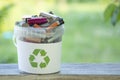 Battery recycle bin with old element on wood table on green grass background