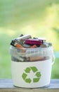 Battery recycle bin with old element on wood table on green grass background