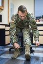 Battle is better in boots. a young soldier tying his boot shoelaces in the dorms of a military academy.