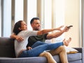 The battle of choosing what to watch. a young couple fighting over the remote control while watching tv at home. Royalty Free Stock Photo