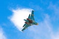 Battle fighter jet aircraft flying dives breaking clouds on a blue sky.