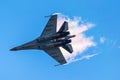 Battle fighter jet flying dives breaking clouds on a blue sky