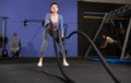 Battle ropes session. Attractive young fit and toned sportswoman working out in functional training gym doing crossfit Royalty Free Stock Photo