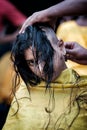 Close-up of young lady devotee getting tonsured or head shaving ritual in Thaipusam Festival.