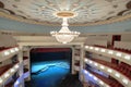 Large chandelier hangs on the theater hall decorated ceiling Royalty Free Stock Photo