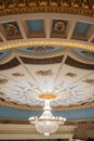 Large chandelier hangs on the theater hall decorated ceiling Royalty Free Stock Photo
