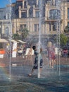 Boy is playing in the fountain. Wet child in the fountain. Splashes of water on a person. Wet clothes on the guy. Royalty Free Stock Photo