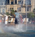 Boy is playing in the fountain. Wet child in the fountain. Splashes of water on a person. Wet clothes on the guy.