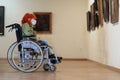 Disabled girl with red hair in a wheelchair visiting the art gallery,