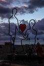 Art work on the coast of the sea depicting the outlines of a man proposing a woman with a red heart in her hands Royalty Free Stock Photo