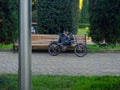 A man with a bicycle is resting on a bench. Rest from sports. Legs on a bicycle frame. Looking at the phone