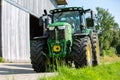 John Deere 6175R tractor drives with a Fliegl Gigant trailer on a dirt road