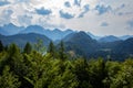The Bavarian landscape with high forest covered mountains and castles are visible under a cloudy summer sky in Hohenschwangau,
