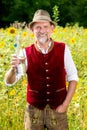 Bavarian man standing in field of sunflowers and holding a bottle of water