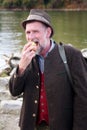 Bavarian man standing by river and eating apple Royalty Free Stock Photo
