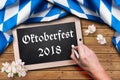 Bavarian tablecloth and a chalkboard with the slogan `Oktoberfest 2018`