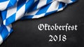 Bavarian tablecloth on slate background with the slogan `Oktoberfest 2018`