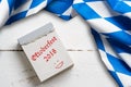 Bavarian tablecloth on wooden background and tear-off calendar with the slogan `Oktoberfest 2018`